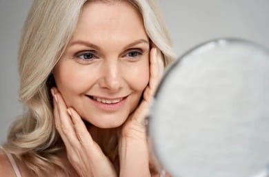 Beautiful woman in her 50s admires her reflection in the mirror.